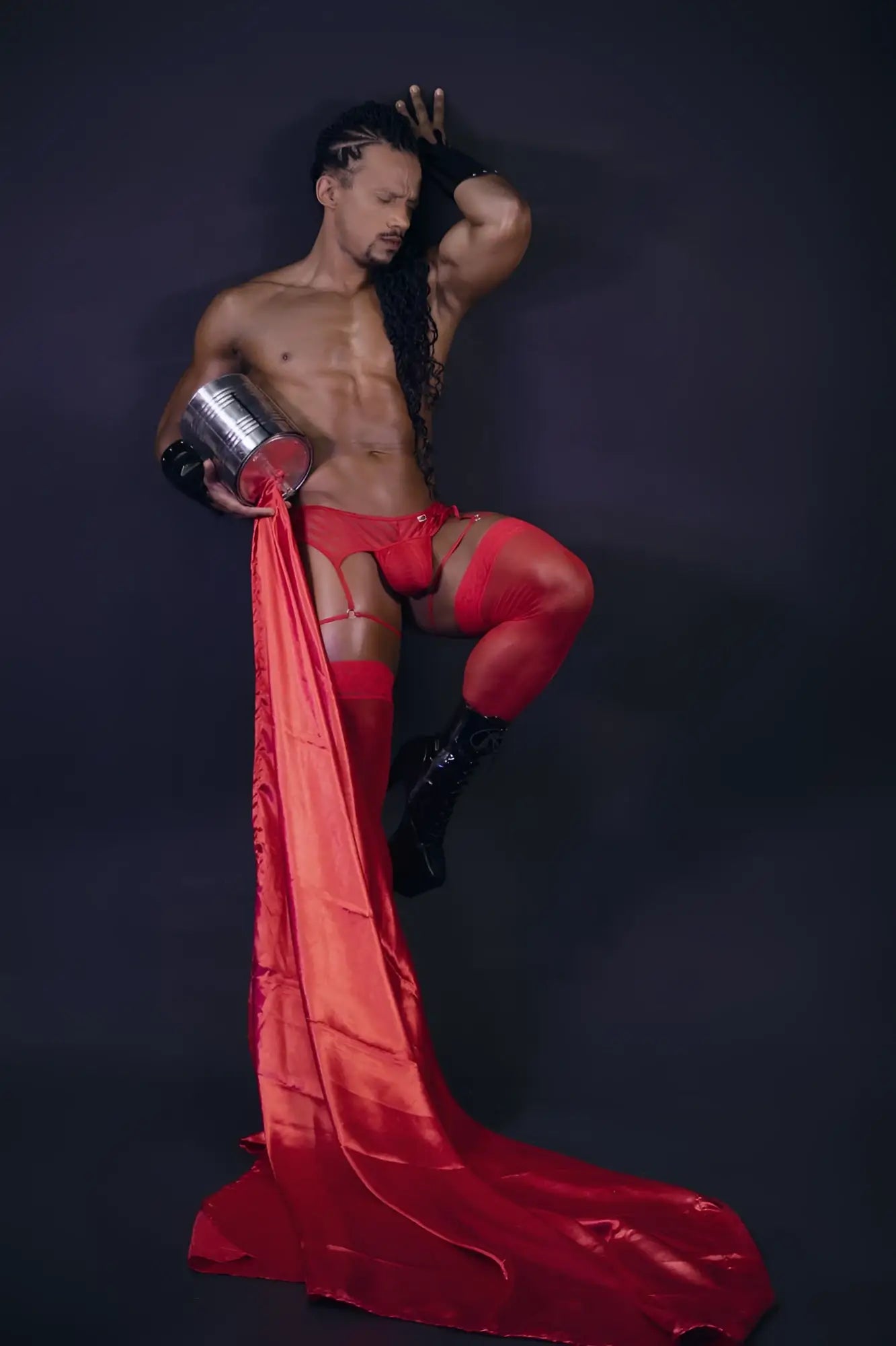 Shiny red satin fabric flowing from a mans leg wearing candyman 99792 mesh garter thongs in red, back side view