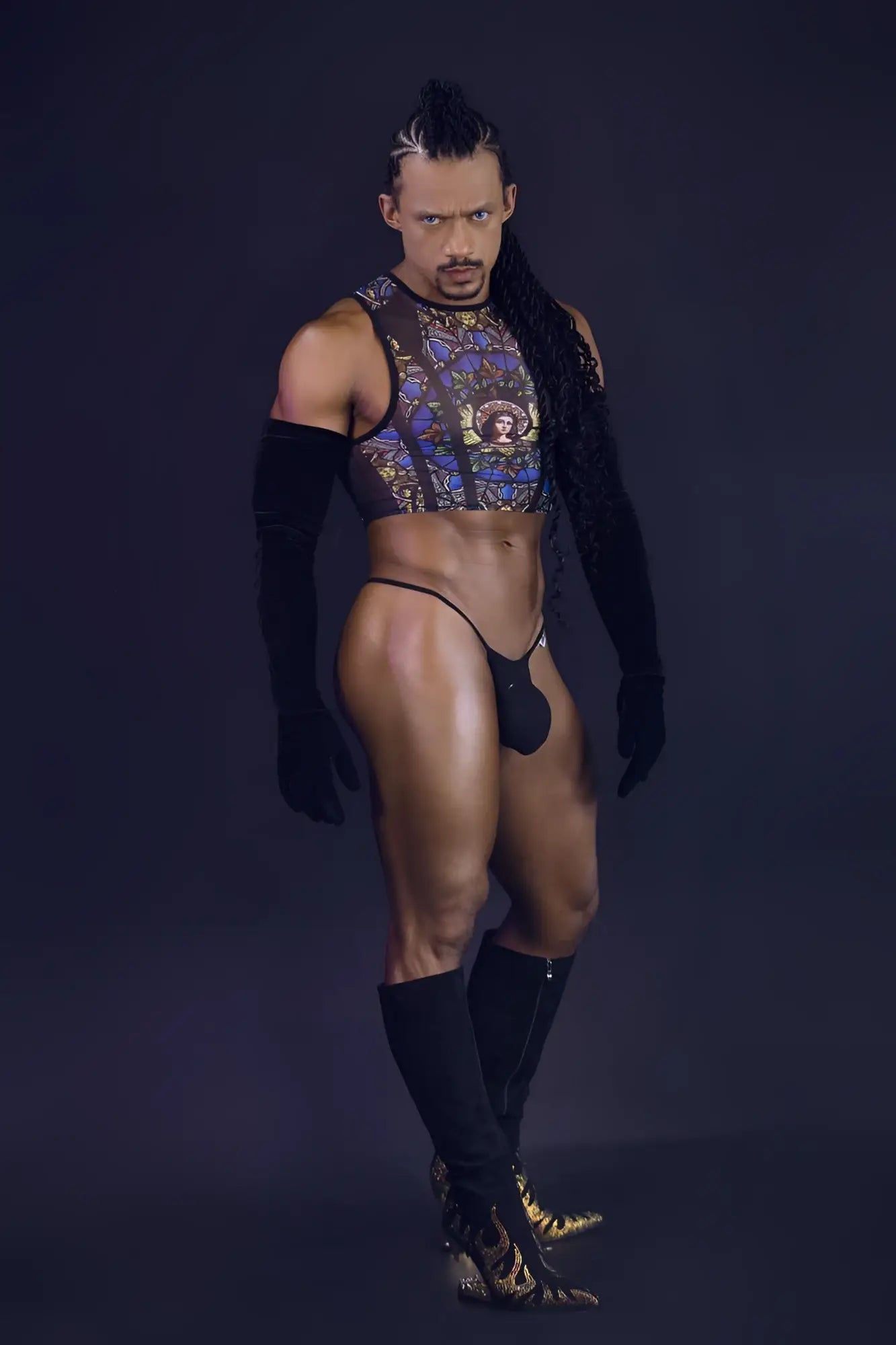 A man wearing a sheer candy man 99805 stained glass tank top with gold and blue patterns over black sleeves