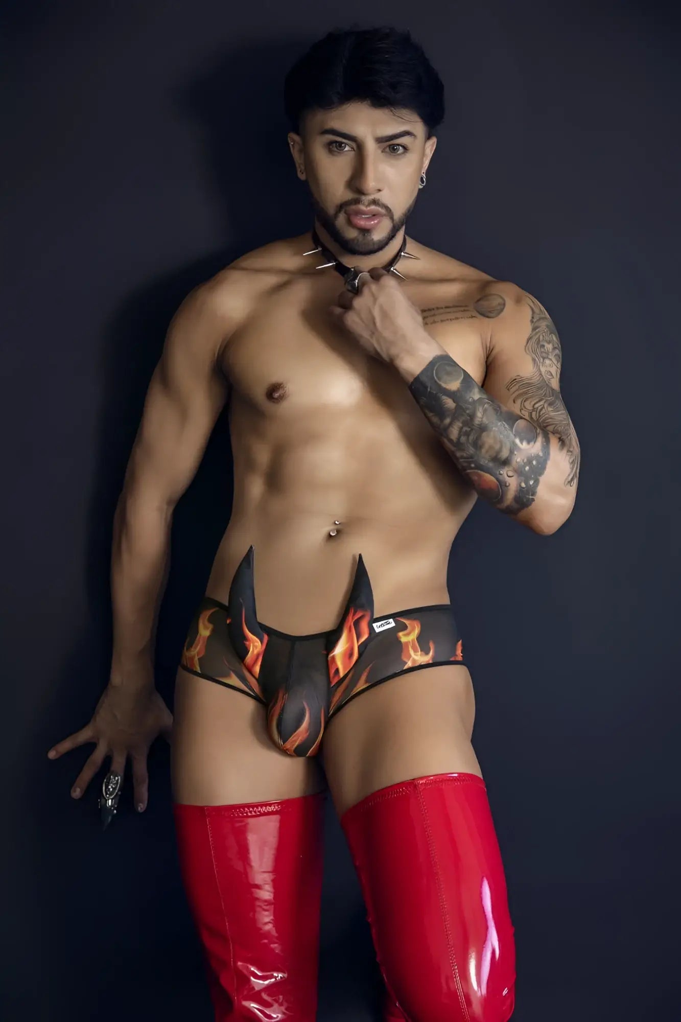 CandyMan 99917 wicked trunks black briefs with black and orange flame pattern paired with glossy red latex thigh-high boot