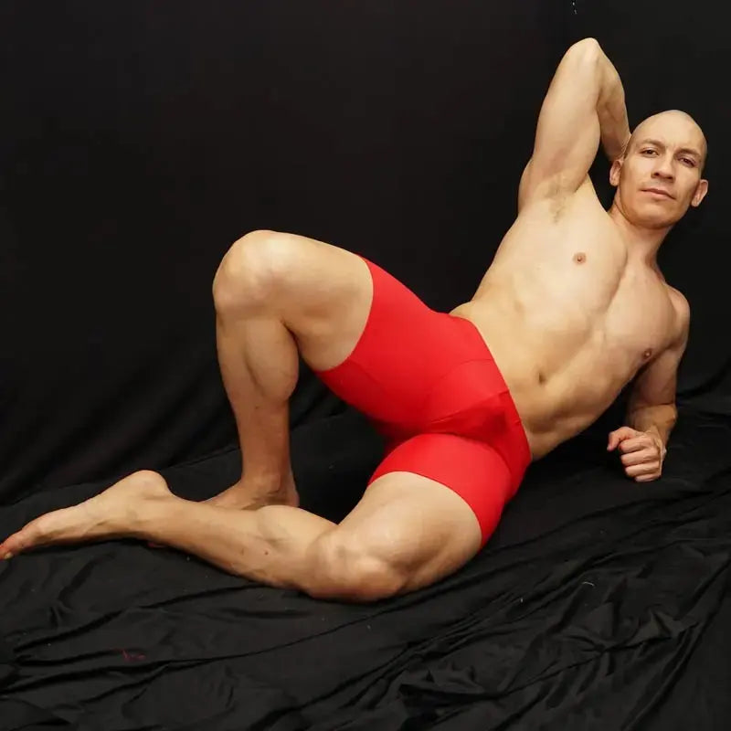 Red compression shorts by Arroyman featuring a snug fit and smooth fabric modeled by a man against a dark background.