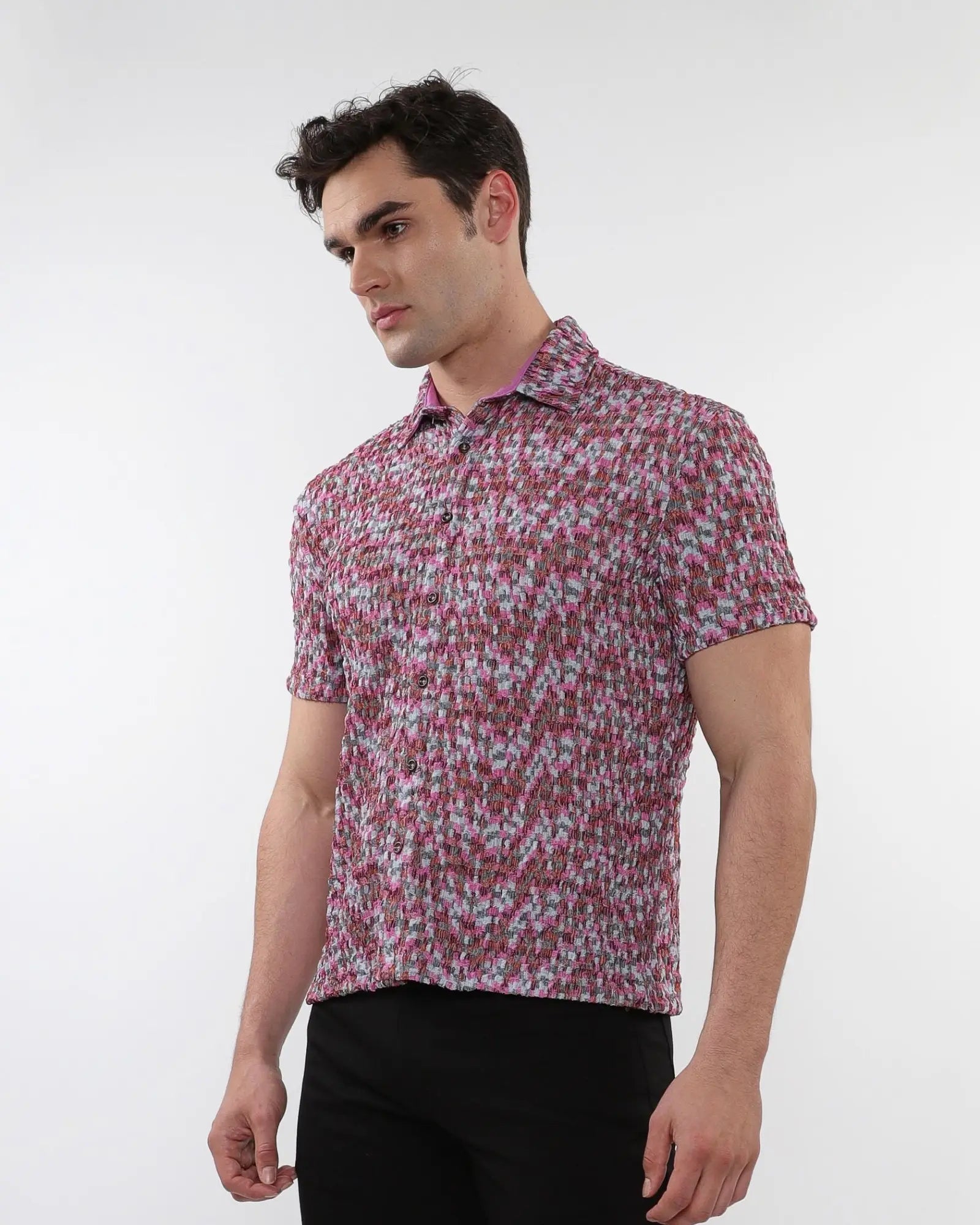 A man wearing a crinkle knit short sleeve shirt with abstract pink and gray textured knit fabric