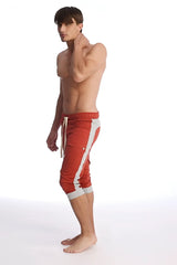 Red cuffed yoga pants in cinnabar with white side stripes and matching drawstring waistband for athletic wear