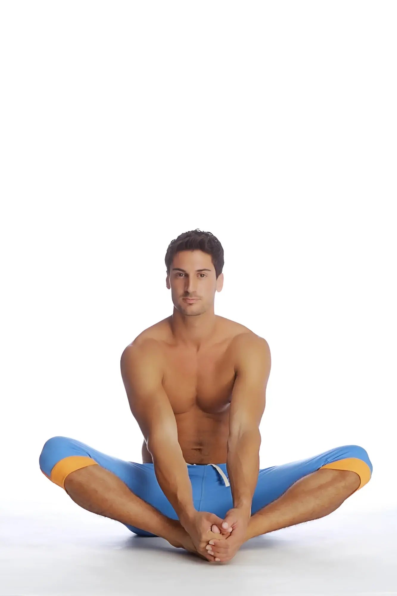 A man wearing cuffed yoga pants in ice blue with orange accents made from bright blue athletic material