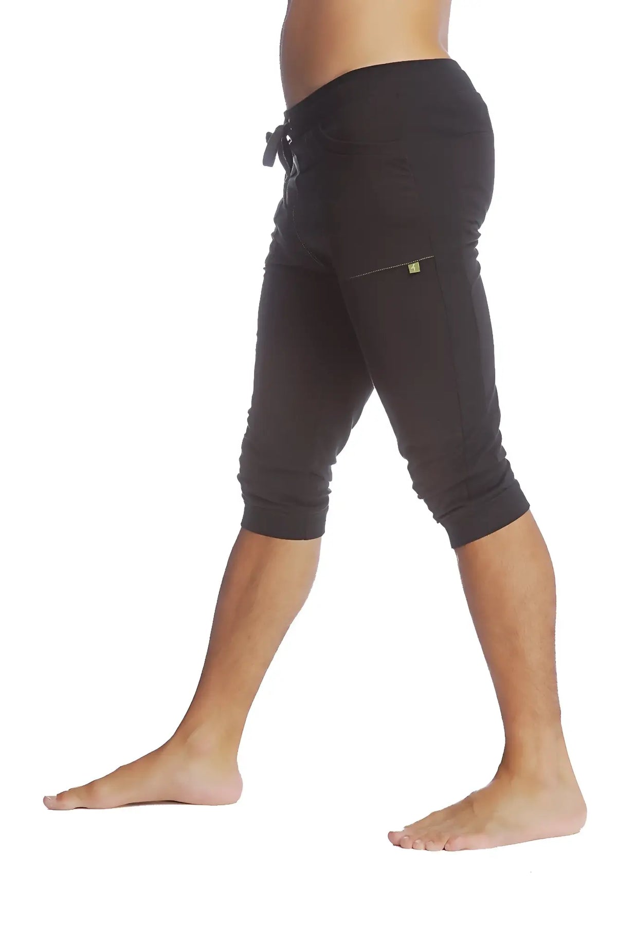 Black cuffed yoga pants with elastic waistband and drawstring featuring a yellow logo on the thigh pocket