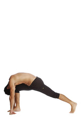 A man in solid black cuffed yoga pants performs a yoga pose against a white background