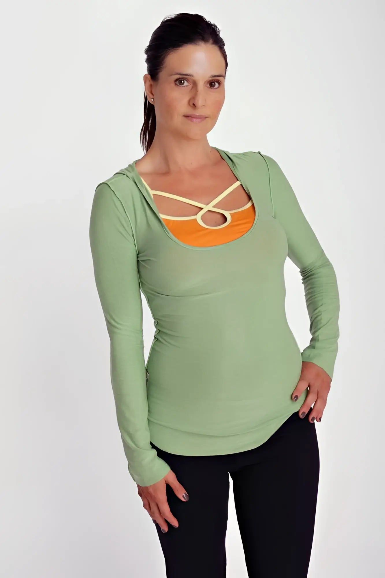 Deep scoop neck long sleeve hoodie top in bamboo green with contrasting orange panel and cream crisscross straps