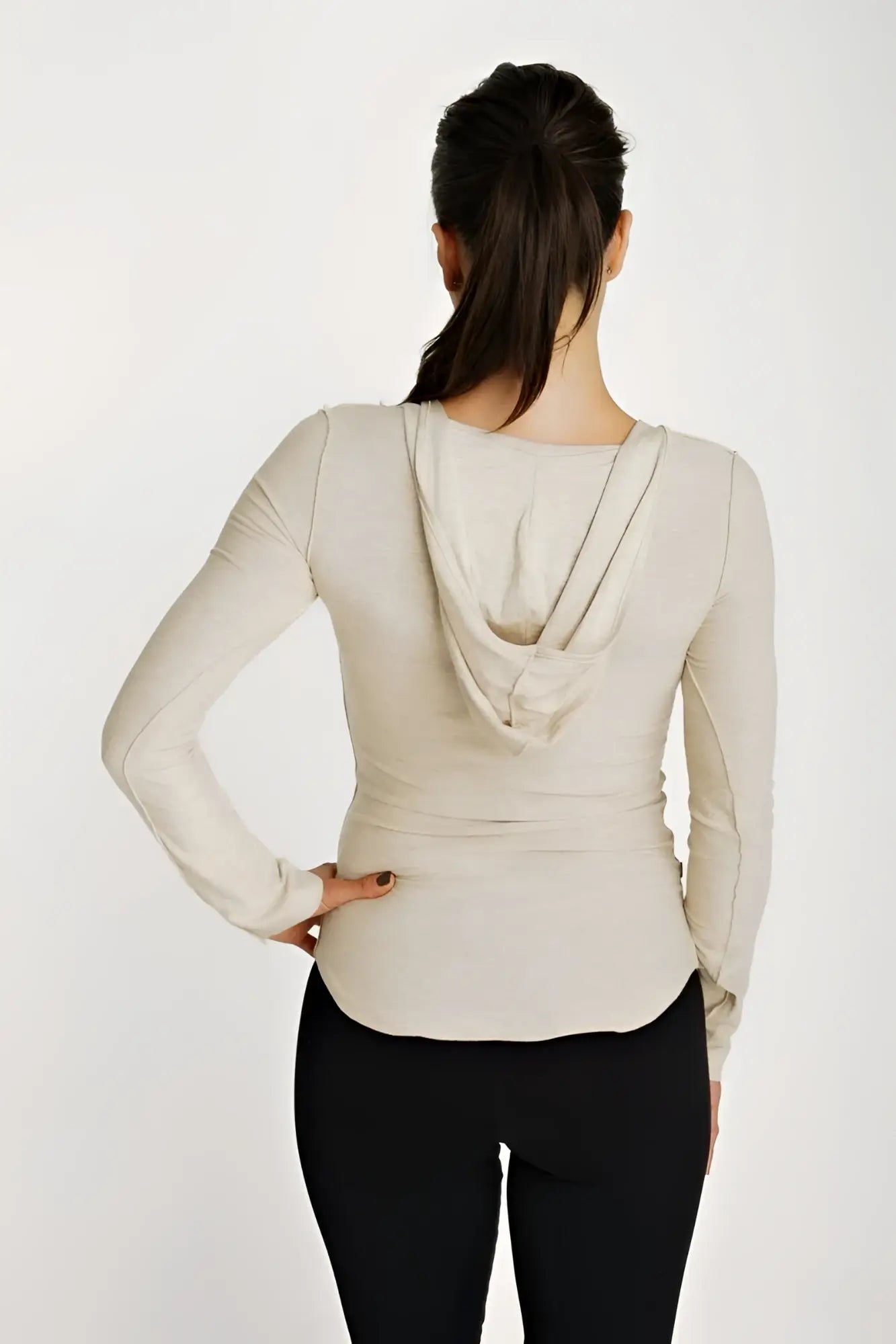 Beige long sleeve hoodie top with deep scoop neckline, draped cowl design, and fitted silhouette in sand beige color