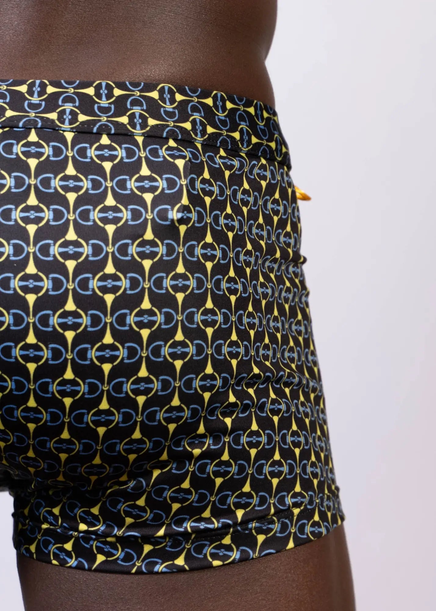 Black designer buckle print sq cut trunk swim trunks with bold interlocking yellow and light blue horseshoe logos