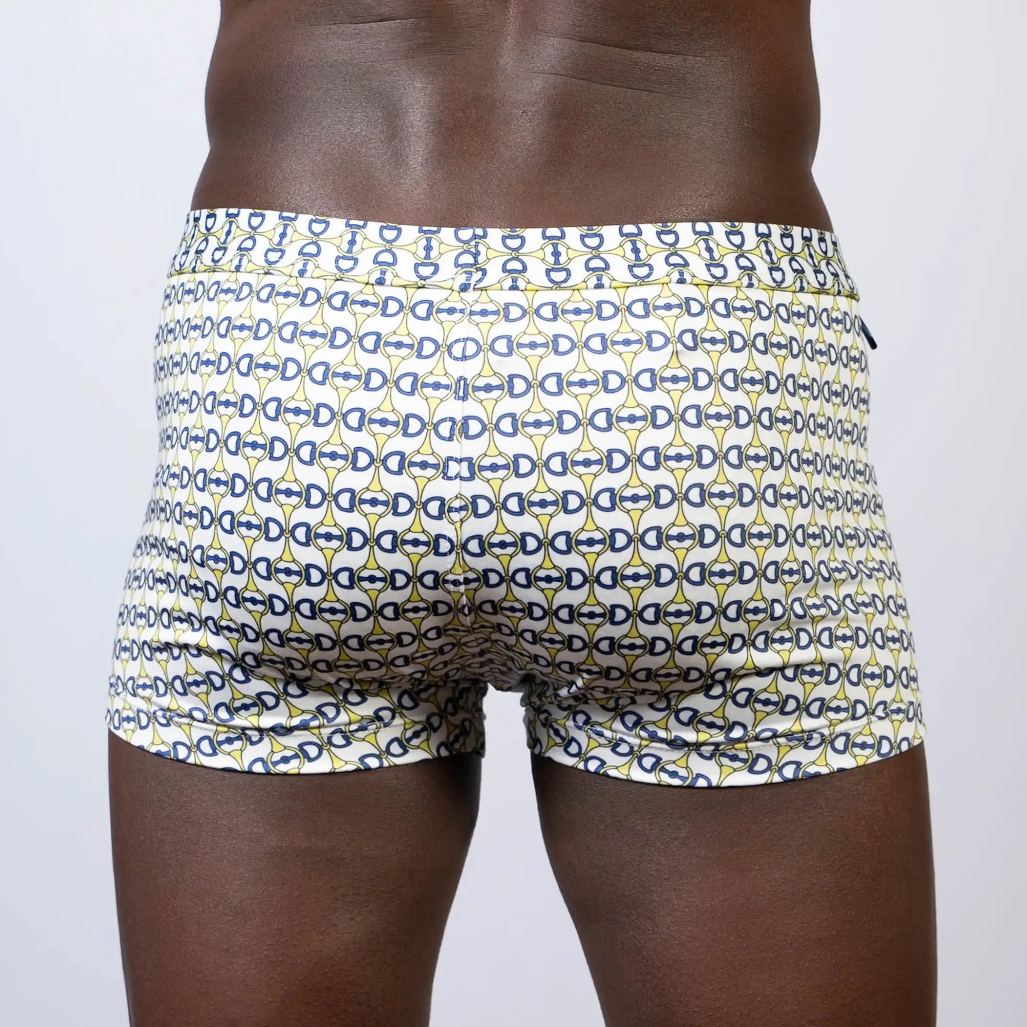 White designer buckle print square cut swim trunks with navy blue and yellow interlocking d-shape patterns