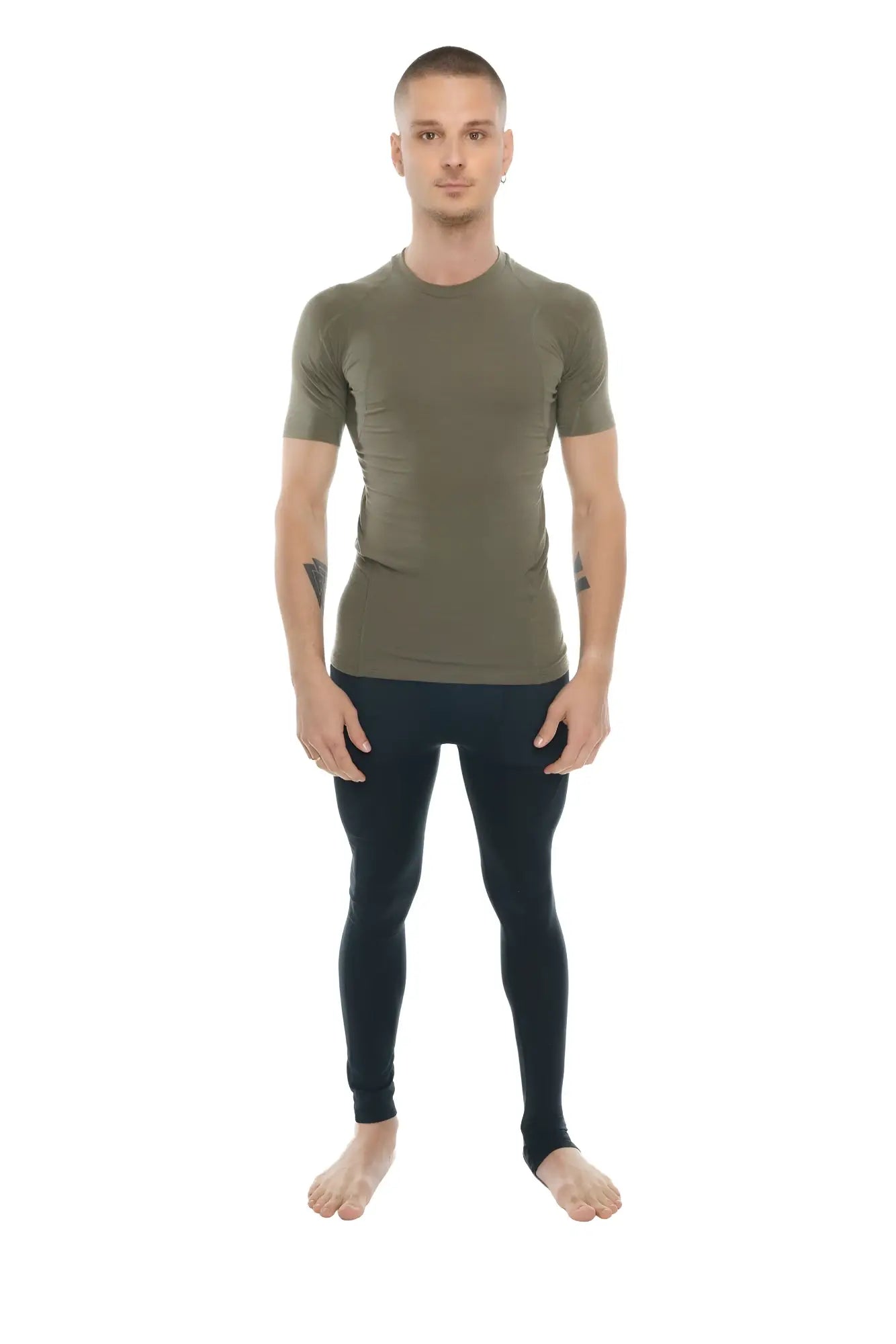 A man wearing a fitted olive green designer raglan crew neck tee with short sleeves paired with black leggings