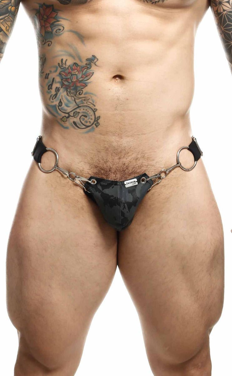Black camouflage-patterned leather strap thong with metal rings shown from the back in DNGEON snap jockstrap style