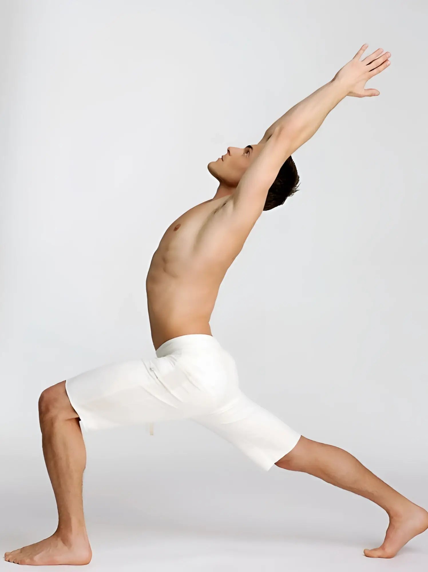 A man wearing white eco-track short yoga shorts in a dynamic stretching pose highlighting form-fitting comfort