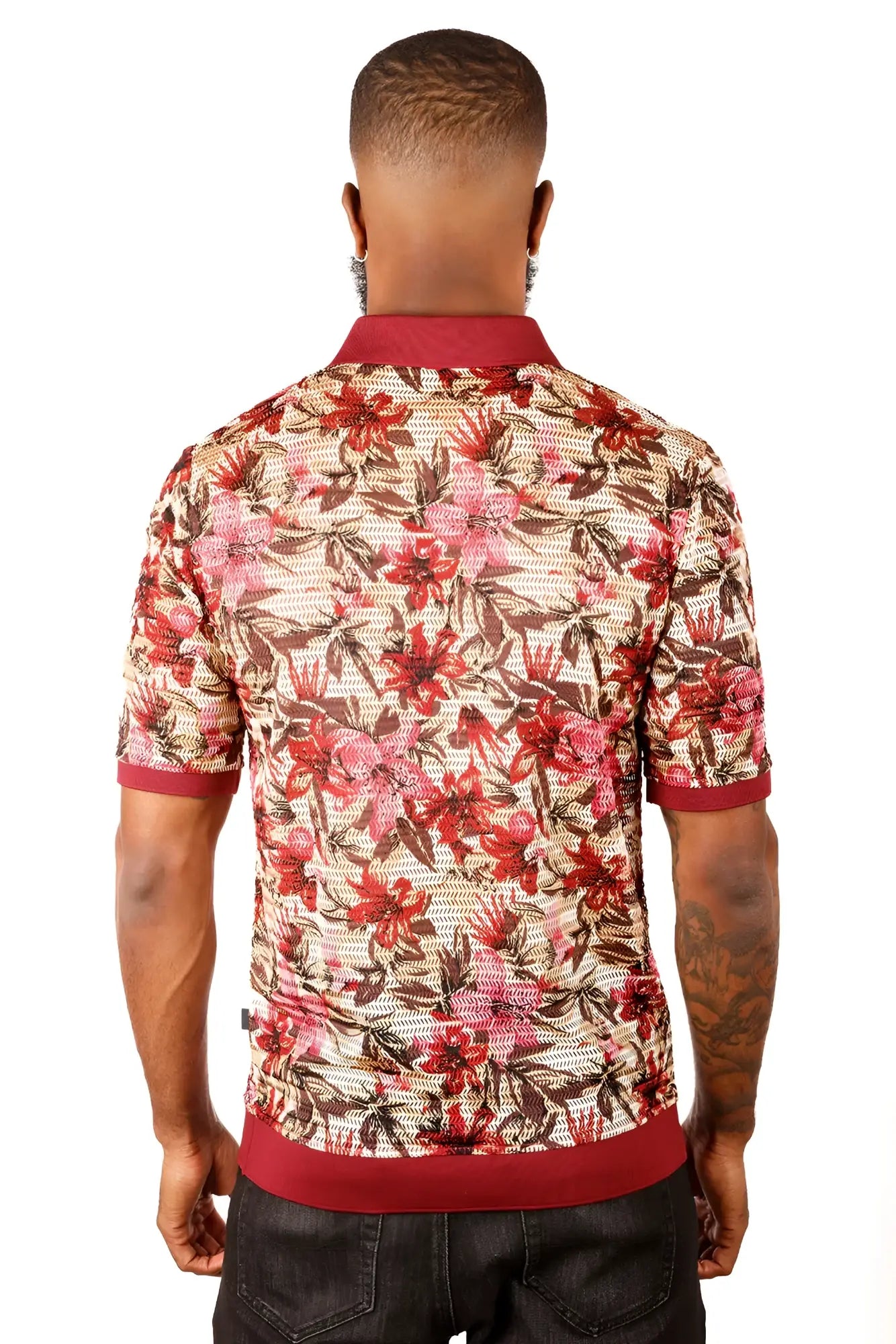 A man wearing an entwine form polo shirt with a vibrant red pink and brown floral pattern on light beige mesh fabric