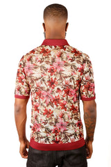 A man wearing an entwine form polo shirt with a vibrant red pink and brown floral pattern on light beige mesh fabric