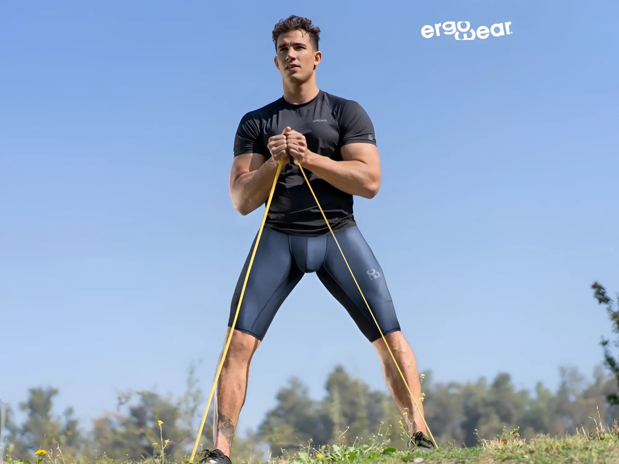 A man wearing ergoWear ew1607 max se dark blue athletic compression shorts holding yellow resistance bands