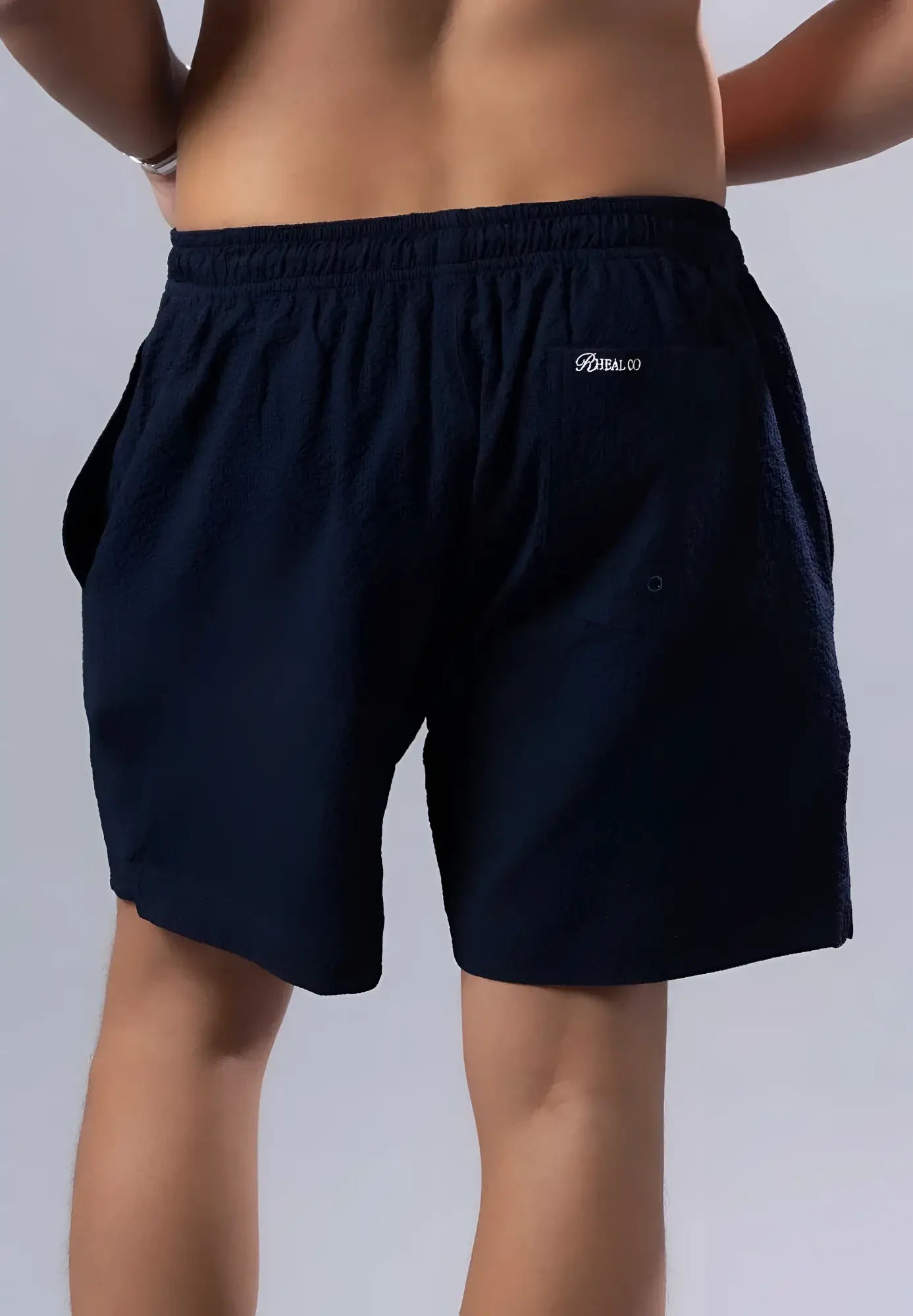 Dark navy blue essential swim short with elastic waistband and embroidered logo on the back pocket shown from behind