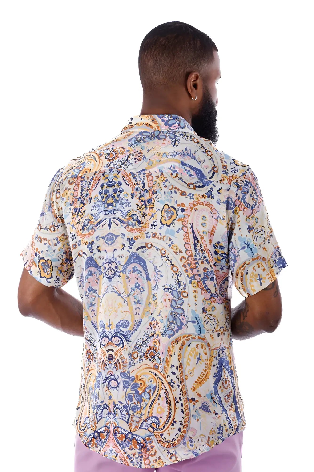 A man wearing an exclusive buzz s/s shirt with blue gold and cream paisley pattern on a light background