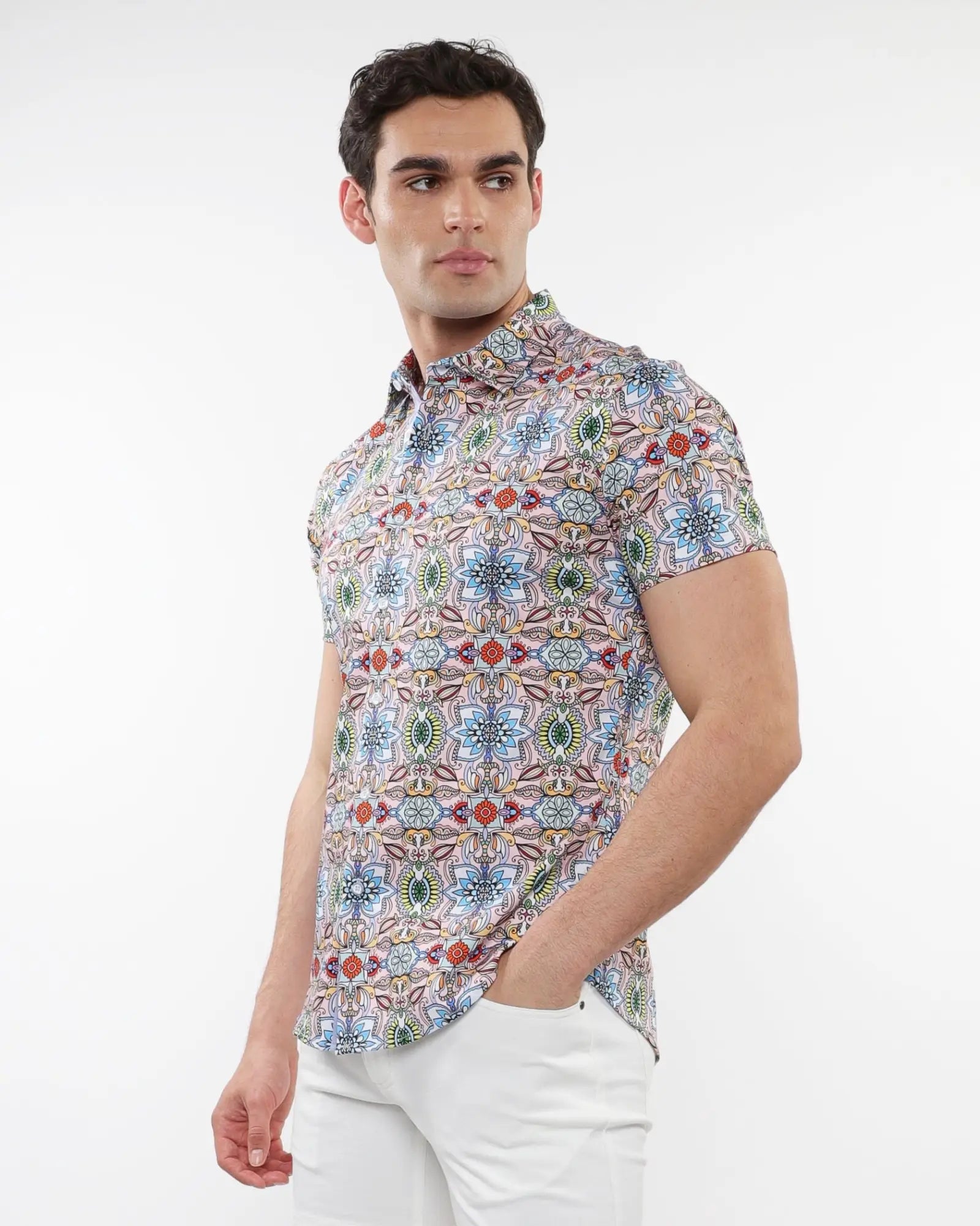 A man wearing a fauna print stretch knit short-sleeved shirt with colorful geometric floral pattern on light background