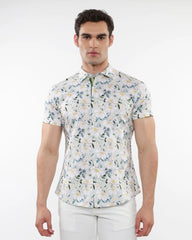 A man wearing a white floral print stretch knit short sleeve shirt with green and yellow delicate patterns