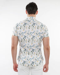 A man wearing a white floral print stretch knit short-sleeved shirt with green blue and yellow patterns