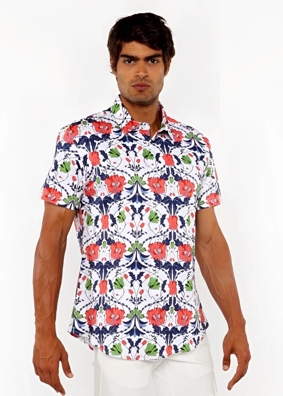 A man wearing a white floral print stretch knit shirt with red poppies green leaves and navy blue accents