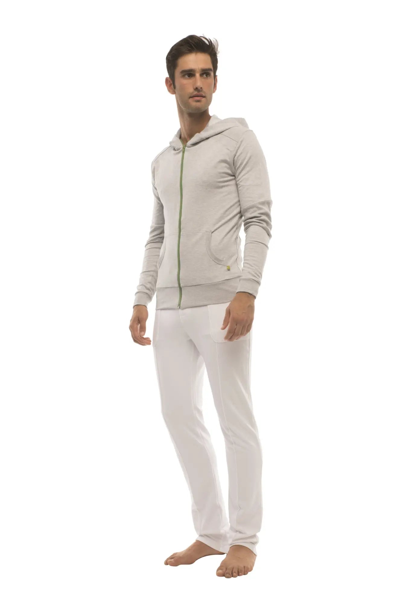 A man wearing a heather gray form-fit crossover yoga track performance hoodie with matching white pants