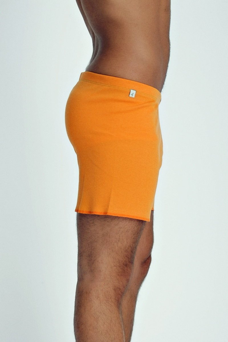 Bright orange ribbed fusion yoga shorts for men with a small white logo on the waistband for active wear