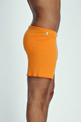 Bright orange ribbed fusion yoga shorts for men with a small white logo on the waistband for active wear