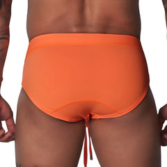 Bright orange swim brief with a wide waistband, contoured back seams, and dangling drawstring against black background.