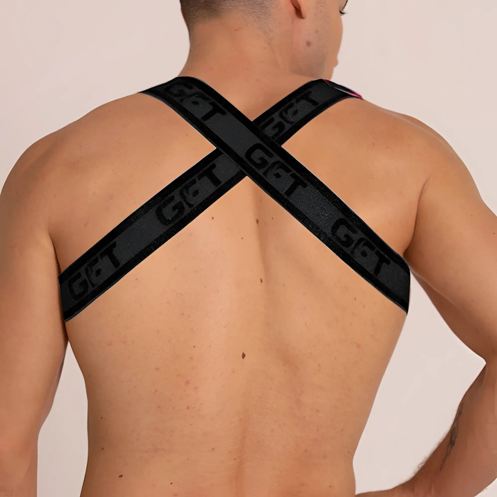 Black gigo fetiche harness back view featuring cross-back straps with get branding in leather material