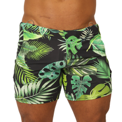 Black swim trunks with vibrant green and lime tropical leaf pattern and metallic silver waistband rings by Gigo Forest