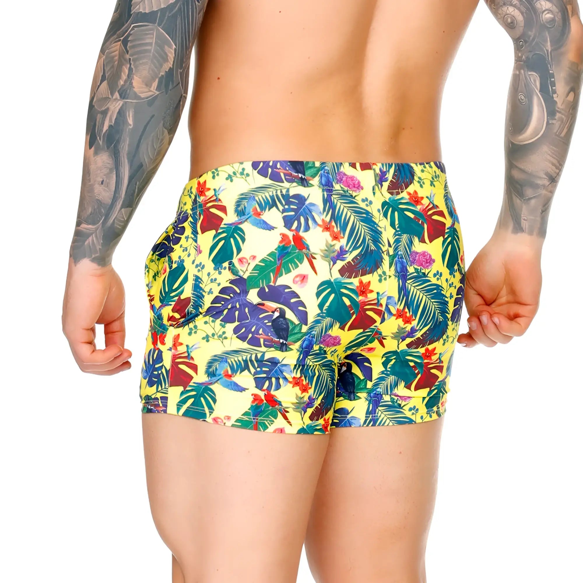 Vibrant yellow Gigo Macaws swim trunks with tropical print of green blue red and purple leaves and birds