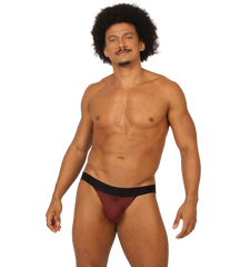 A man wearing a snug fit gigo mix wine jockstrap in maroon and black showing the front side of the product