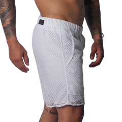 White athletic shorts made of a sheer, open-mesh material with an elastic waistband and small black logo patch.