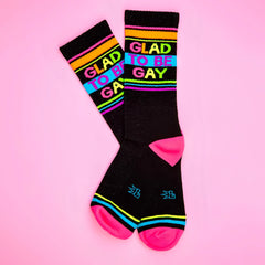 Black crew socks with vibrant rainbow stripes and bold colorful glad to be gay lettering for pride wear