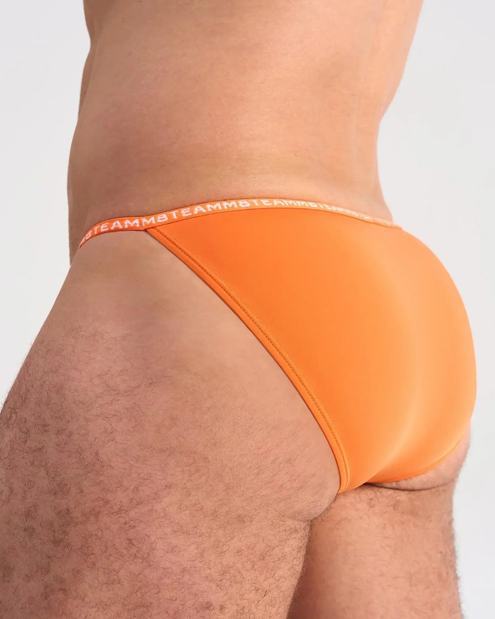 Bright orange glide micro brief featuring soft fabric and a matching elastic waistband with brand logo repeat