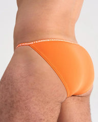 Bright orange glide micro brief featuring soft fabric and a matching elastic waistband with brand logo repeat