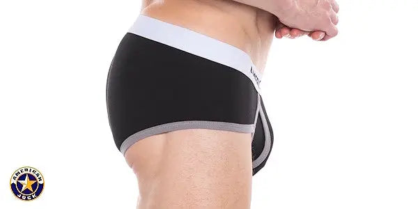 Side view of a man wearing black classic brief with white waistband and gray trim by AMERICAN JOCK