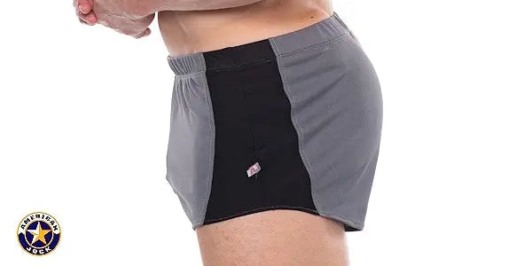 Side view of a man wearing AMERICAN JOCK men's sprint shorts in black and gray with a small logo tag on the front panel
