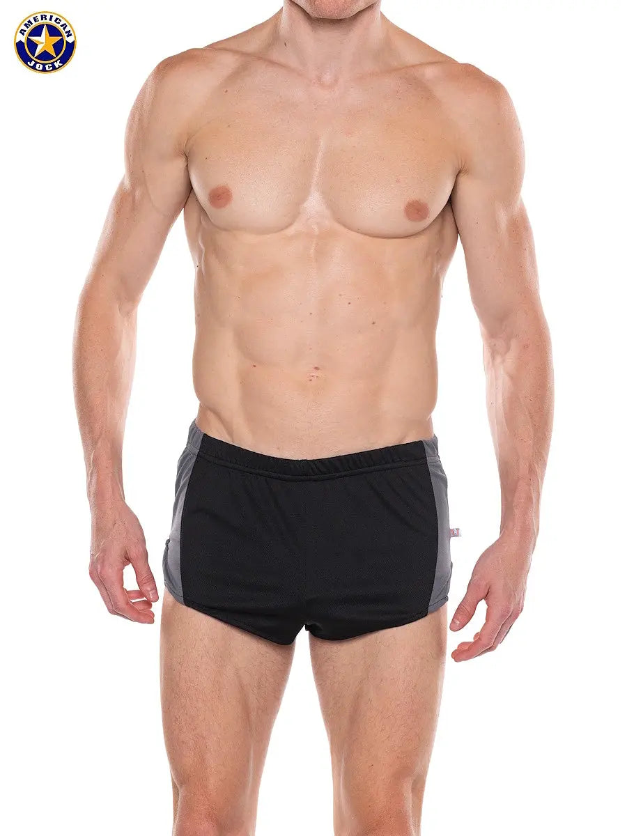 Male model wearing black and gray athletic sprint shorts with elastic waistband by AMERICAN JOCK