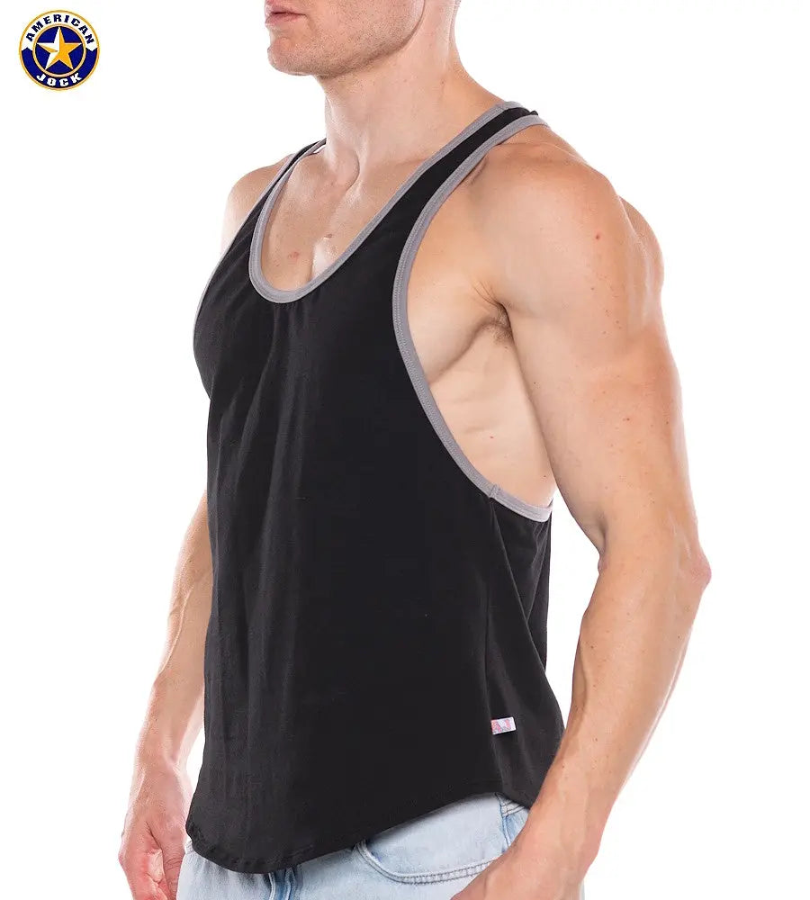 Muscular man wearing black tank top with gray trim and deep armholes paired with light blue jeans by AMERICAN JOCK