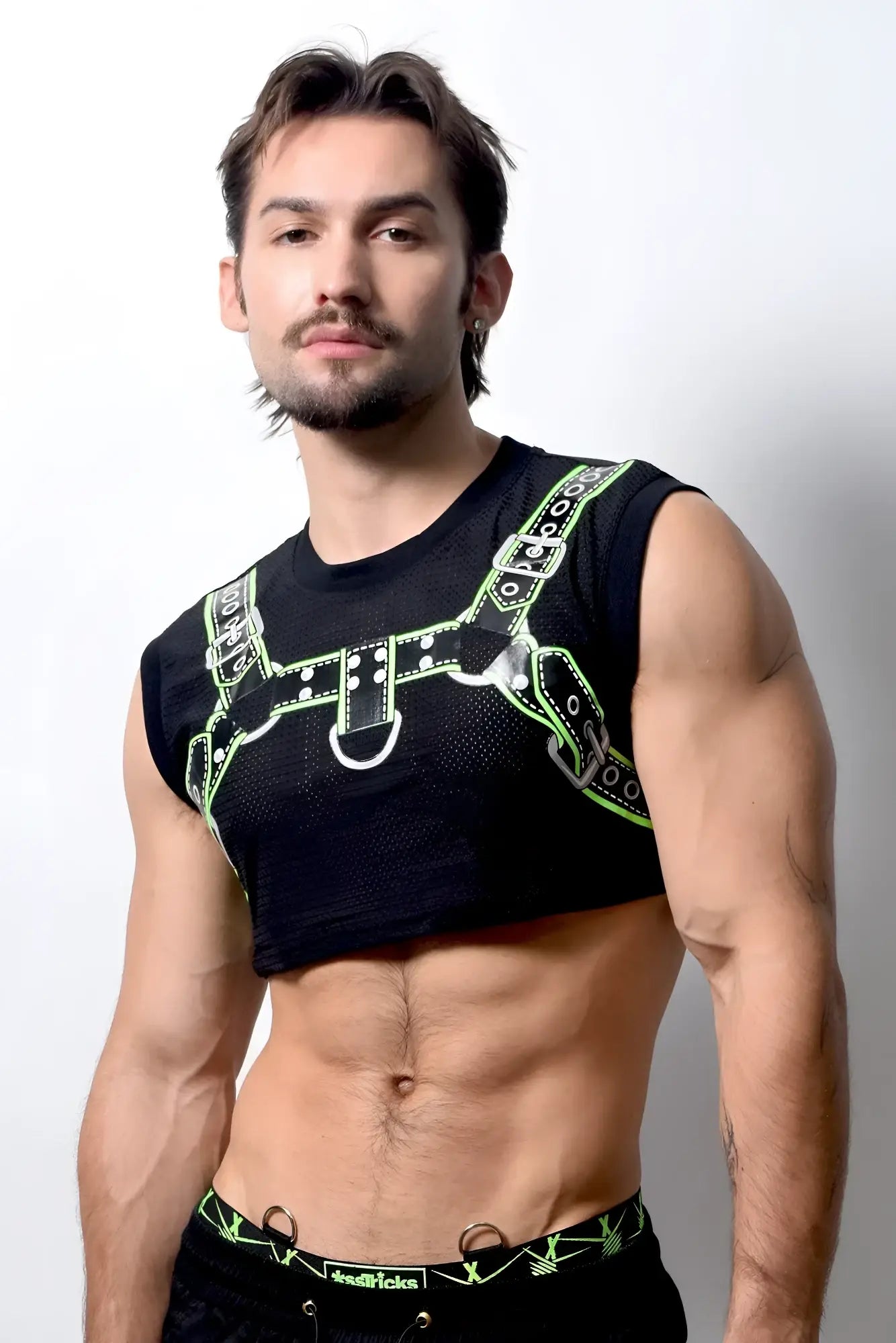 Harness crop top featuring black mesh with neon green leather-like straps and silver hardware detailing