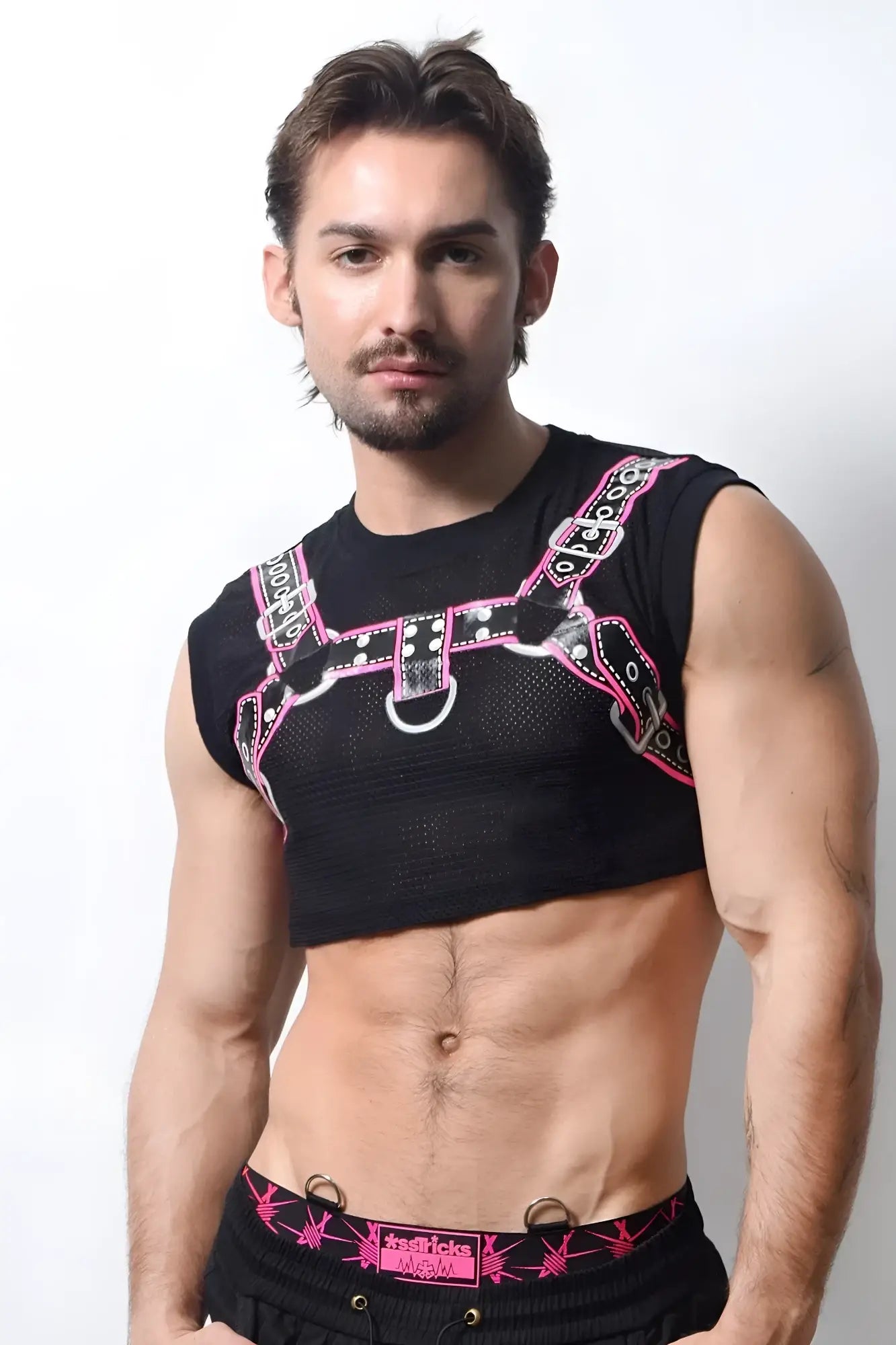 Black mesh harness crop top with pink and black straps and silver hardware detail in front view