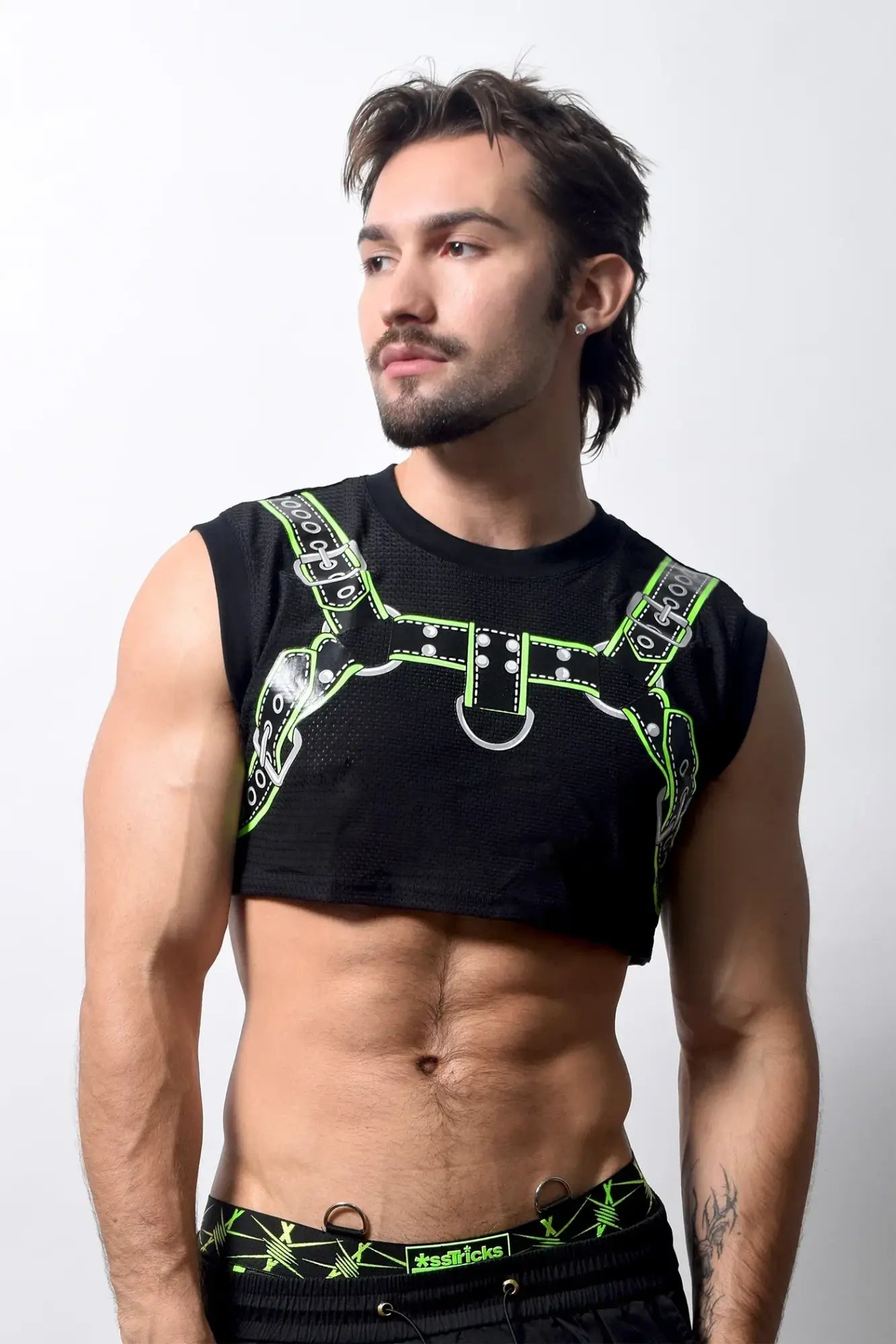 Black harness crop top with neon green leather-like straps and silver hardware featured from the back side