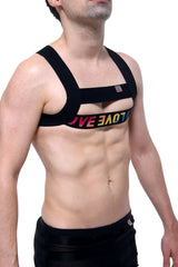 Black petitq givet love chest strap harness with rainbow-colored love lettering across the front
