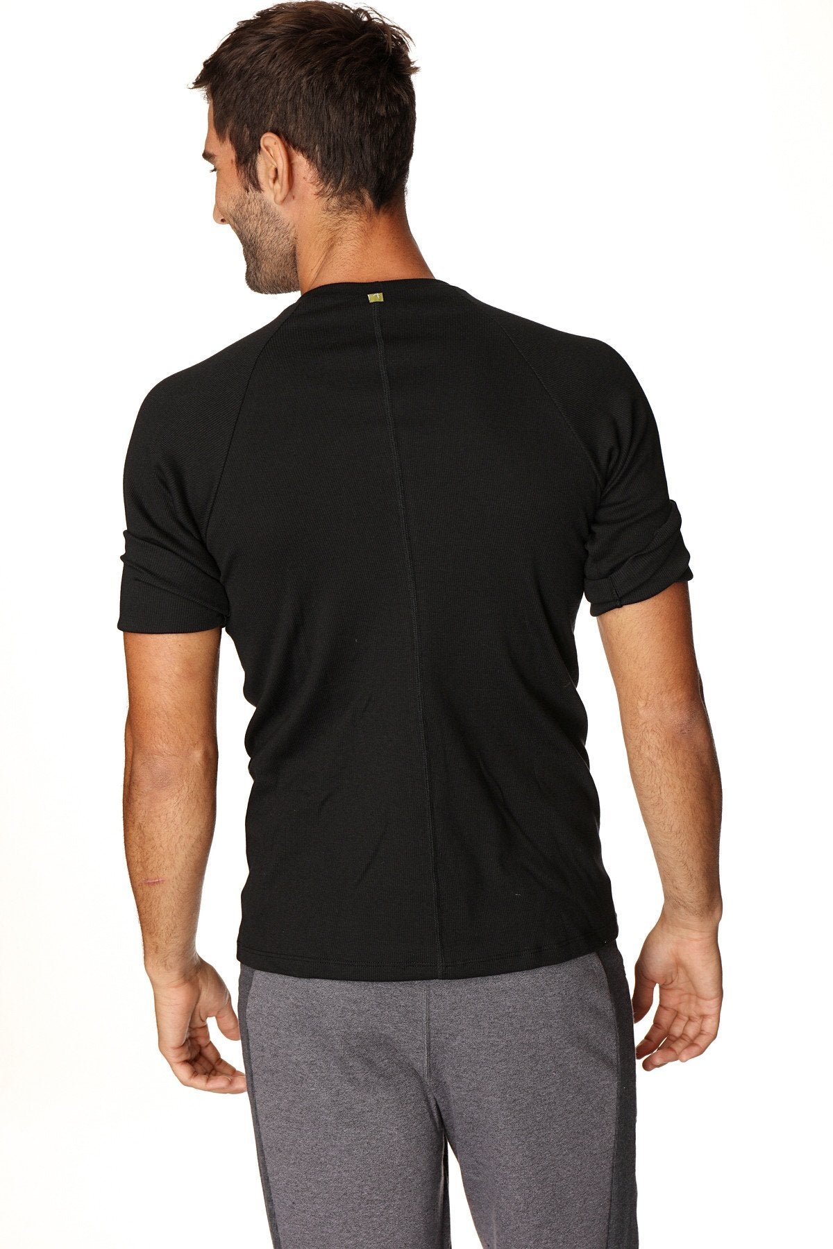 Black hybrid crew neck raglan tee back view with short sleeves, subtle vertical seam, and small green neckline logo