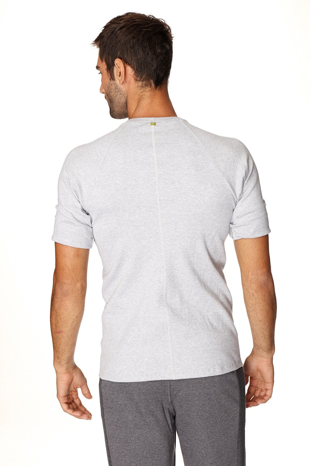Back view of hybrid crew neck raglan tee in heather grey with subtle vertical seam and small green logo at neckline