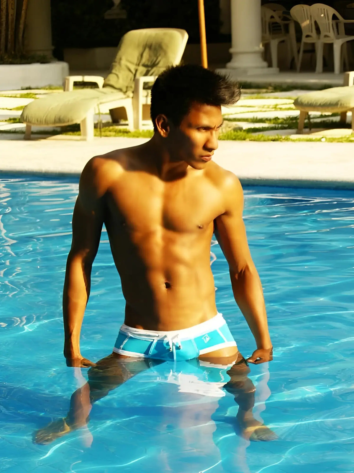 A man wearing icker sea cord contrast trim and stitching bikini swimwear in blue and white standing in a pool