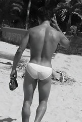 White briefs swimwear by icker sea duotone bikini swimwear red worn by a man on a beach front view