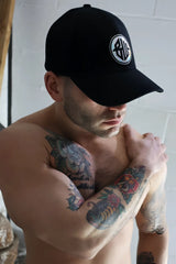 Black baseball cap with white circular logo featuring stylized lettering on the front called illuminator icon hat